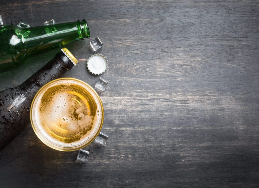 Beer glass with bottle cap and bottle on rustic wood background,