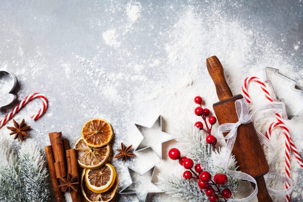 Bakery background for cooking christmas baking with rolling pin, scattered flour and spices decorated with fir tree top view.