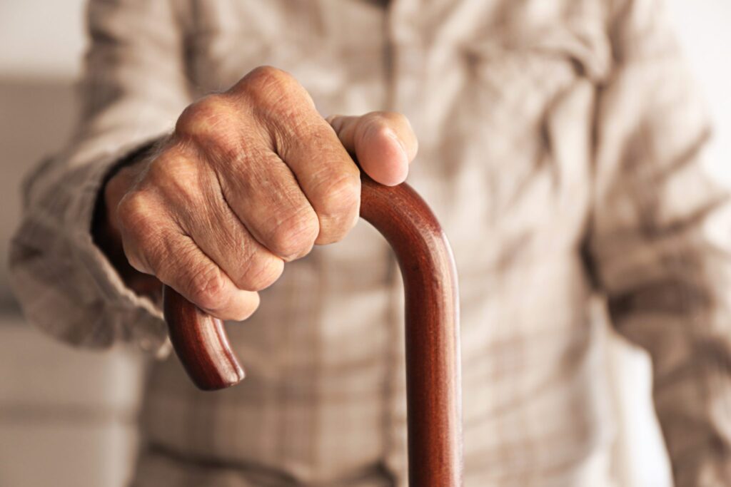 Old man hand holding walking stick