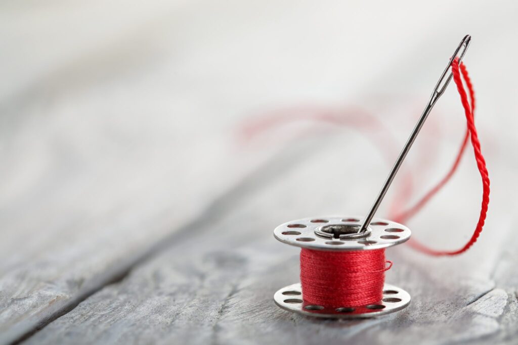 bobbin with a red thread and a needle