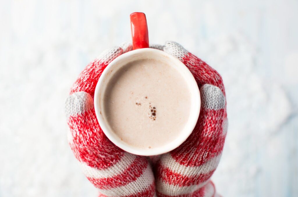 female hands in gloves holding hot chocolate