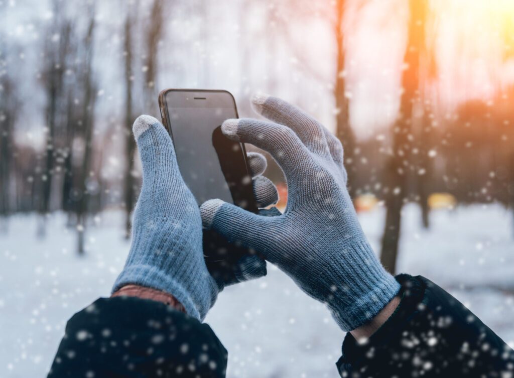 Man using smartphone in winter with gloves for touch screens